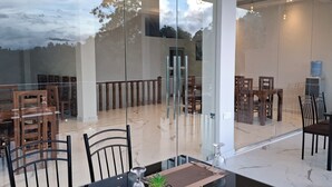 Un comedor moderno con divisiones de vidrio, muebles de madera y un dispensador de agua.