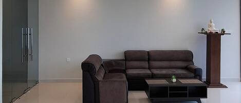 Una sala moderna con un sofá seccional, una mesa de centro y una escultura decorativa sobre un pedestal.