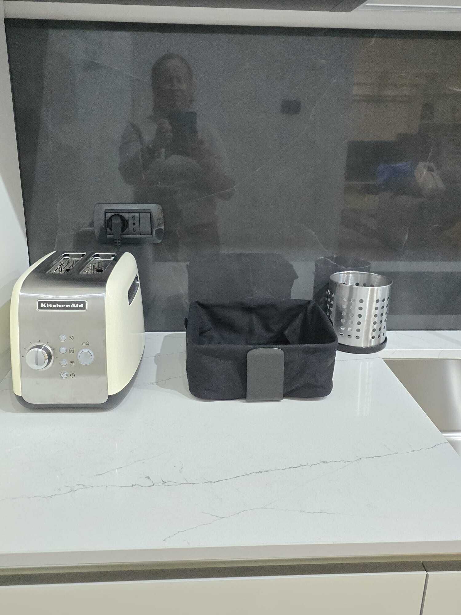 A kitchen counter with a KitchenAid toaster, a black bag, and a metal colander.
