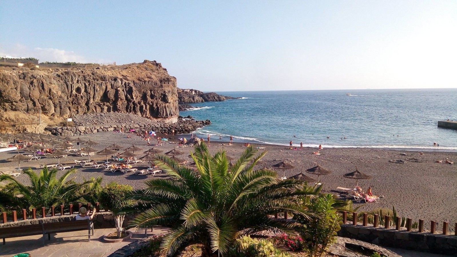Une plage bordée de falaises rocheuses, avec des parasols et des chaises longues.