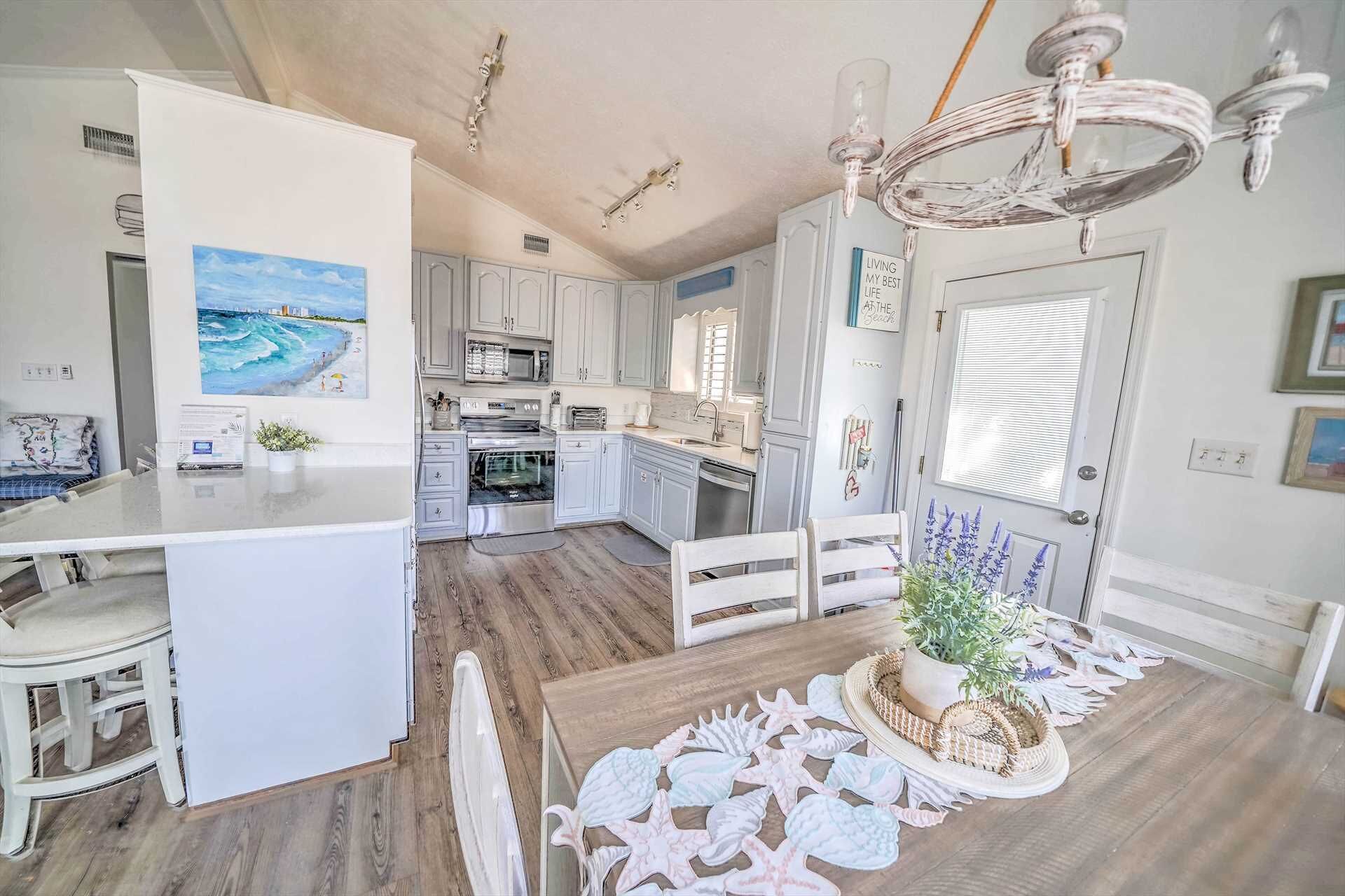 Una cocina amplia con armarios blancos, una isla central y un comedor con mesa y sillas de madera.