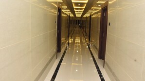 Un long couloir élégant, doté de revêtements de sol réfléchissants et d’un éclairage encastré.
