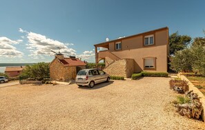 A two-story house with a stone extension, a gravel driveway, and a parked car. - 3 bedroom awesome apartment in Maslenica (Maslenica)