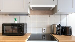 Une cuisine moderne avec un micro-ondes noir, une cuisinière blanche et une machine à café posée sur le plan de travail.