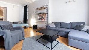 Un salon moderne avec un canapé gris, une table basse noire et un tapis gris à motifs.