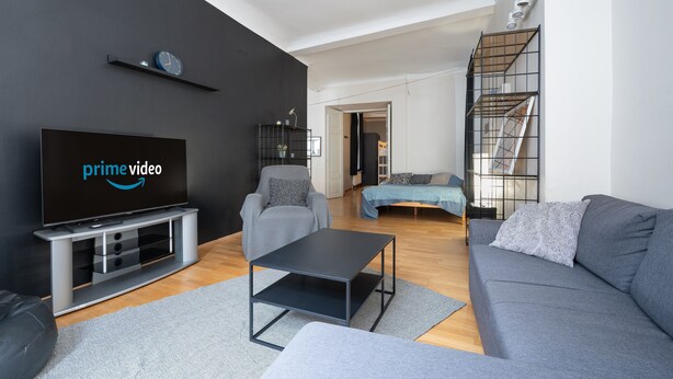 Un salon moderne avec un téléviseur à écran plat, des canapés gris, une table basse et un escalier.