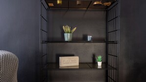Une étagère en métal noir avec deux plantes en pot et un petit récipient en métal.