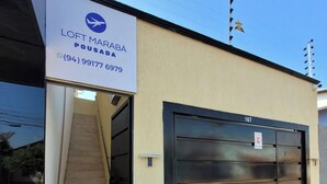 A building with a sign reading "LOFT MARABA POUADA" and a phone number. There is a black garage door with the number 167 on it.