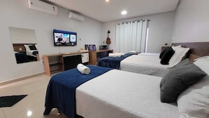 Habitación de hotel con dos camas, un escritorio, un televisor y una guitarra.