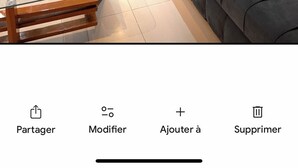A modern living room with a grey sofa, a glass coffee table, and a flat-screen TV mounted on a wooden wall. - Apparently delux in a complex with three pools (Cabo Negro)
