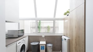 A laundry room with a washing machine, dryer, and two trash bins. - Central & Spacious 2BR in Almada • Easy access to Lisbon (Almada)