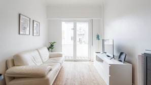 A modern living room with a beige sofa, a white console table, and a flat-screen TV. - Central & Spacious 2BR in Almada • Easy access to Lisbon (Almada)