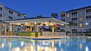 A poolside bar with a covered seating area, a pool with lane markers, and adjacent multi-story buildings. - Coastal Retreat Awaits at Holiday Inn Club Vacations South Beach Resort- 2 Bd. (Myrtle Beach)