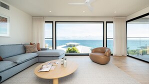 Ein modernes Wohnzimmer mit großem Fenster, einer Couch, einem Couchtisch und einem Ledersessel.