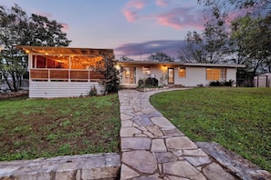 Una casa de dos plantas con un sendero de piedra que lleva a la puerta principal.