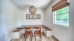 A dining area with a table, two chairs, a sign that says "SWIM", and a window with a view of greenery. - Lakefront Near Schlitterbahn and New Braunfels (McQueeney)