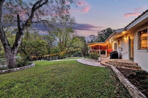 Una casa con un porche cubierto, un sendero de piedra y luces colgantes.