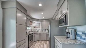 A modern kitchen with grey cabinets, a granite countertop, and stainless steel appliances. - Lakefront Near Schlitterbahn and New Braunfels (McQueeney)