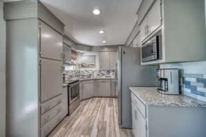 A modern kitchen with grey cabinets, a granite countertop, and stainless steel appliances. - Lakefront Near Schlitterbahn and New Braunfels (McQueeney)