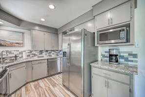 Una cocina moderna con electrodomésticos de acero inoxidable, un salpicadero de azulejos y una encimera de granito.