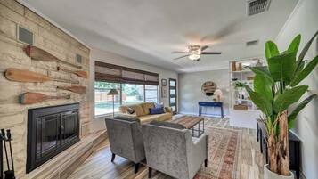 A living room with a fireplace, a stone wall, and a ceiling fan.