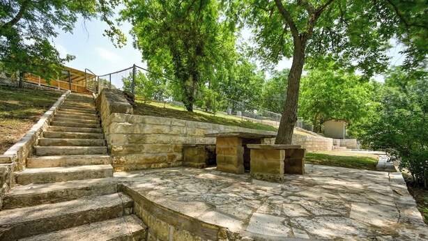 A stone staircase leading up a hill, surrounded by trees and a stone platform with benches. - Lakefront Near Schlitterbahn and New Braunfels (McQueeney)