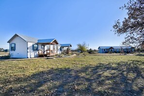 A row of cabins with a grassy field in the foreground and a clear sky.