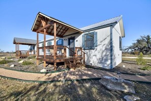 Ein modernes Haus mit einer Holzterrasse, einer überdachten Veranda und einem kleinen Garten.