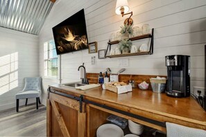 A kitchen with a wooden countertop, a coffee maker, and a wall-mounted TV.