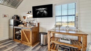 Una cocina con una isla de madera, electrodomésticos de acero inoxidable y un amplio ventanal con persianas.