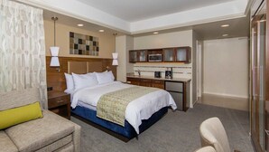 Quarto de hotel com cama, mesas de cabeceira, escrivaninha, cadeira e guarda-roupa.