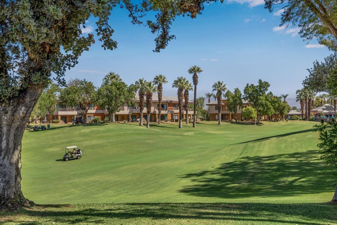 Ein Golfplatz mit Clubhaus und Palmen.