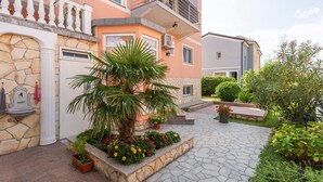Un patio con una fuente de piedra, una palmera y macizos de flores.