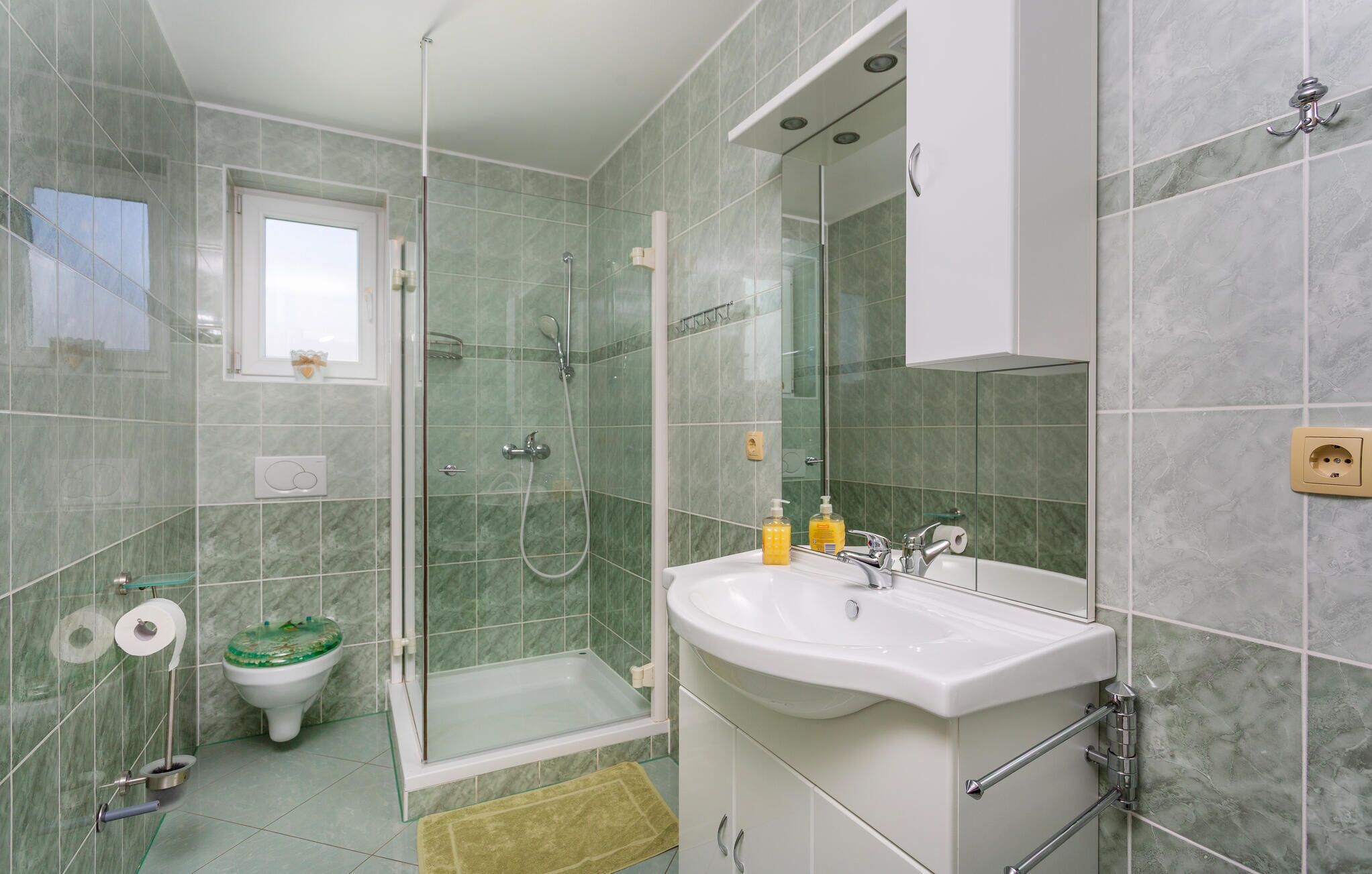 Une salle de bain avec une douche à parois de verre, des toilettes et un lavabo avec un miroir.
