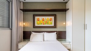 A modern hotel room with a large bed, a framed painting above the bed, and a bedside table with a mirror. - Apto 2 Qtos c/ Churrasq. a 650m da praia ESP0301 (Florianópolis)