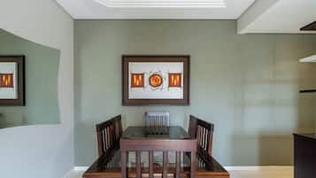 A dining area with a rectangular table and six chairs, a framed abstract painting above the table, and a staircase leading to an upper level.