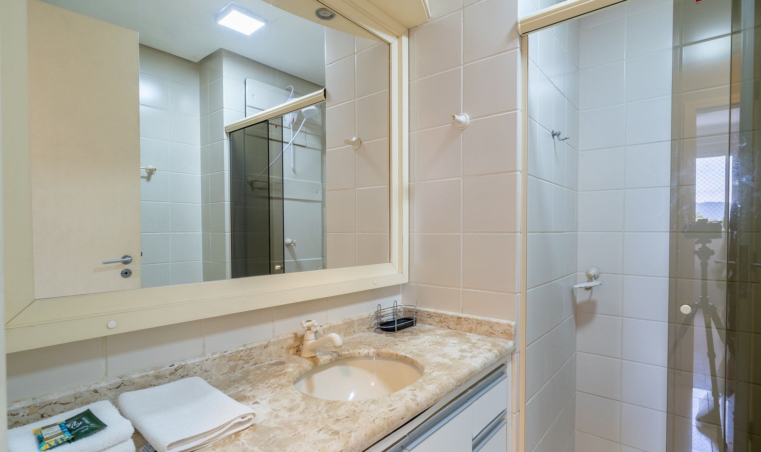 A bathroom with a large mirror, a sink, and a shower.
