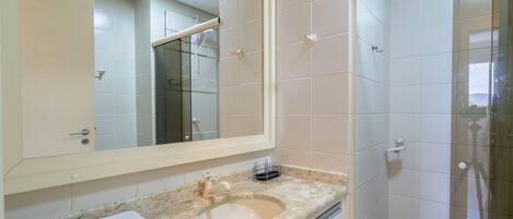A bathroom with a large mirror, a sink, and a shower.