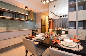 A modern kitchen with a dining area set for a meal. - Studio em frente a UFSC e HU - CEN010 (Florianópolis)