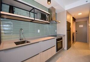 Een moderne keuken met een ingebouwde magnetron, een roestvrijstalen spoelbak en een vaatwasser.