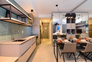 Uma cozinha moderna com área de jantar integrada, com forno embutido, pia e mesa de jantar posta para seis cadeiras.