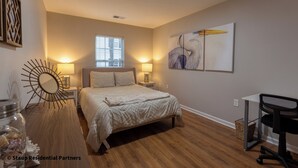 A bedroom with a bed, bedside lamps, a desk, and a chair.