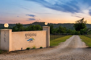 Ein Schotterweg führt zu einem verschlossenen Eingang mit einem Schild für 'River's Edge Cottages at Morris Ranch'.