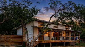 Ein zweistöckiges Haus mit einer Holzterrasse und einem großen Baum davor.