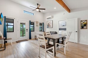 A dining area with a table and chairs, a ceiling fan, and a view of the outdoors through a window.