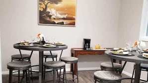 A dining area with two round tables, each with four chairs. There is a painting on the wall above the tables.