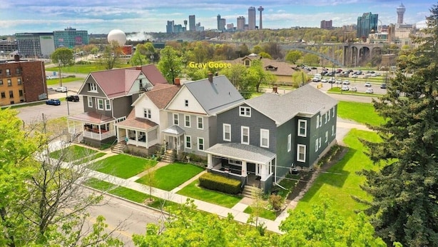 A residential area with houses, a large green lawn, and a city skyline in the background.