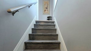 A staircase with wooden steps and a handrail, leading to a landing with a framed artwork.