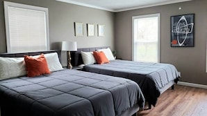 A bedroom with two beds, a nightstand, a lamp, and a framed picture on the wall.