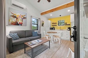 A modern living room with a sofa, coffee table, and artwork. - Winecup Cottage (Fredericksburg)